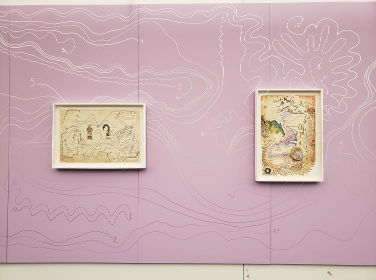 Two of the framed artworks are seen against a larger pink artwork that covers the wall they are hung on. The pink artwork is covered in squiggly lines in the style of the others