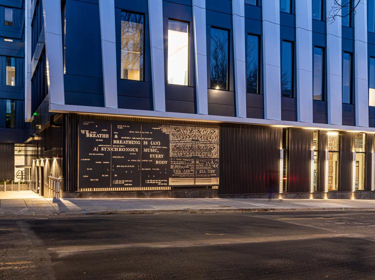 Wide angle image of the artwork at night including the street and Vanport Building