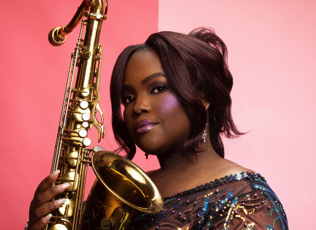A beautiful woman with her hair in a bun and she is holding a saxophone