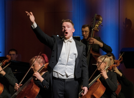 Photo of a performer on stage with cellists