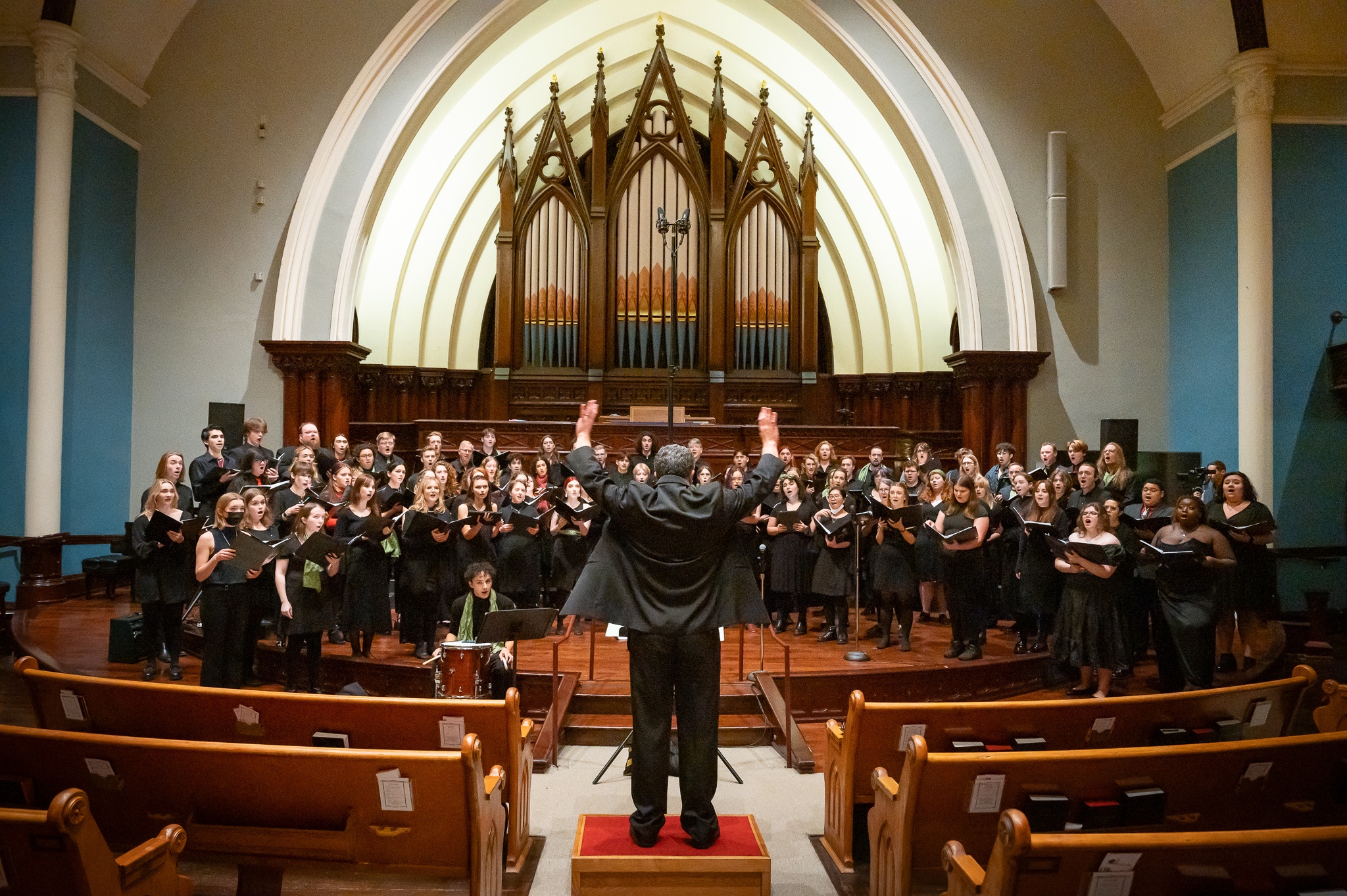 PSU Choirs performing in a church with Ethan Sperry conducting.