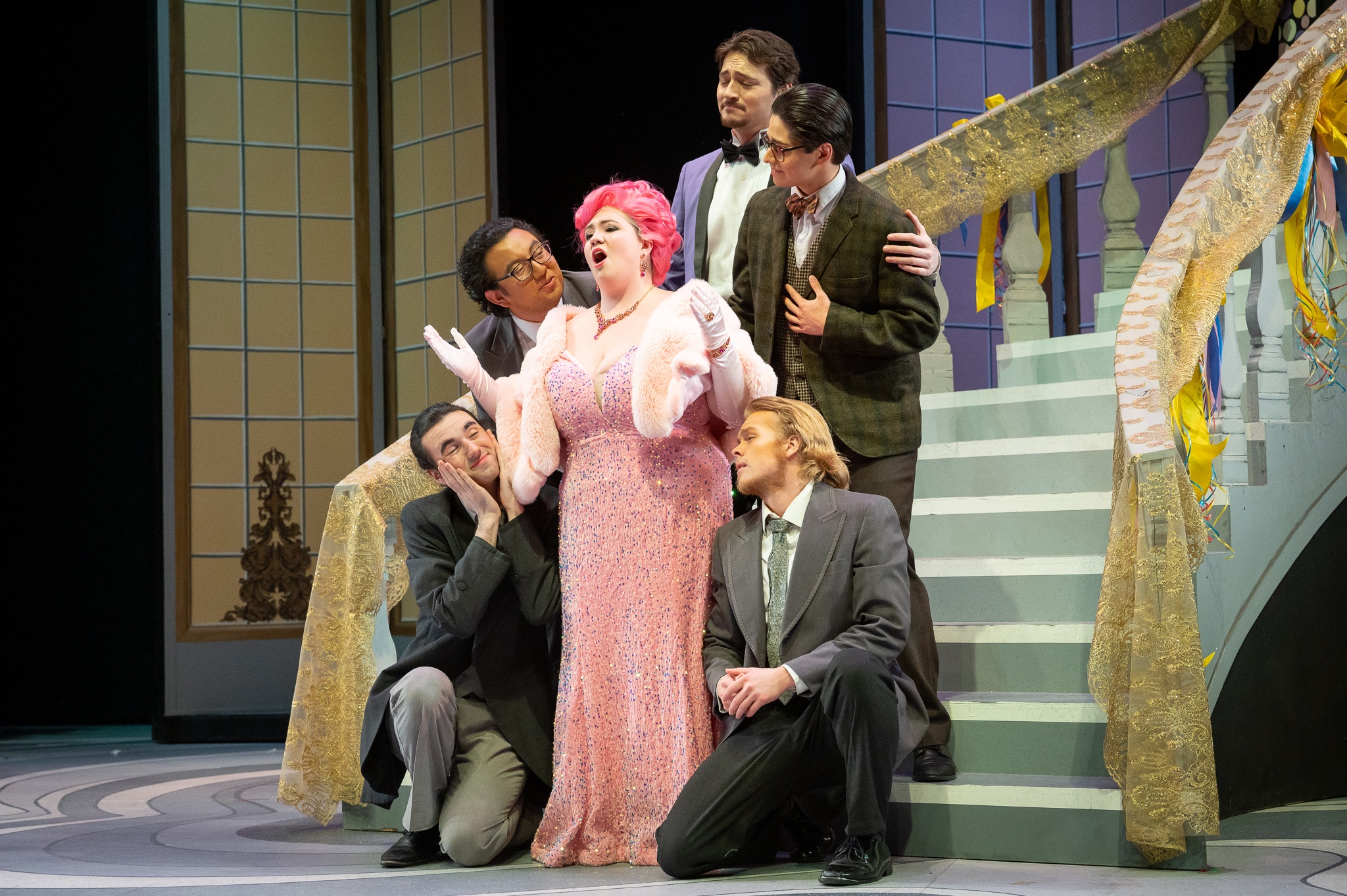 PSU Opera students performing in "The Merry Widow" with a large winding staircase behind them on the Lincoln Performance Hall stage.