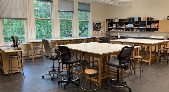Lincoln Hall room 307 with tall islands of tables for students to work on theater designs as groups. View of the Park Blocks trees outside the window.