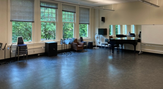 Lincoln Hall room 321. Large empty linoleum floor with chairs and piano along the sides. Mirror on one wall and view of tree tops along the other wall.