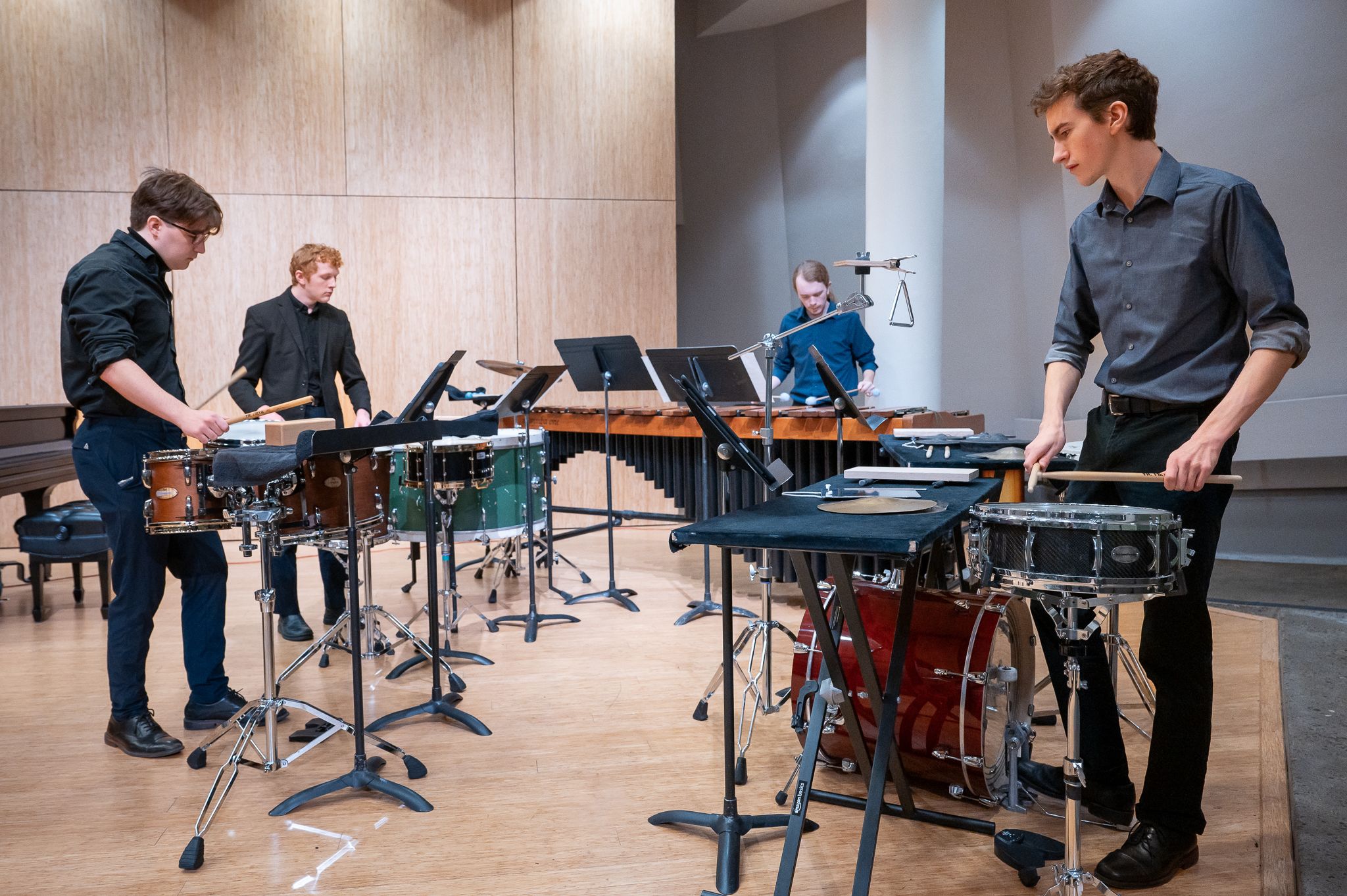Four PSU Percussion students performing in Lincoln Recital Hall with a collection of drums and marimbas.