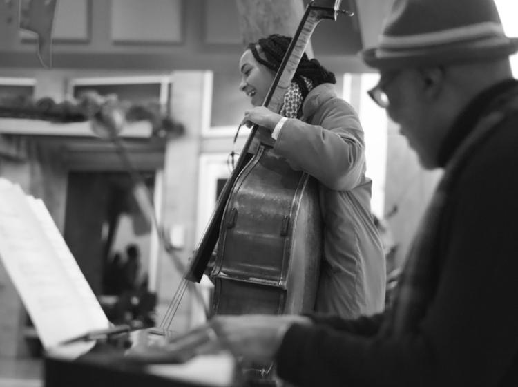 A student playing cello, and Darrell Grant playing the piano.
