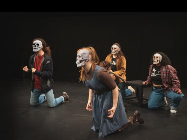 Actors are kneeling with emoji skulls covering their faces. Their hand gesture is angry or desperate.