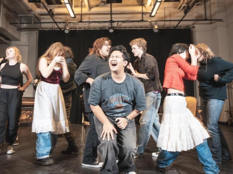 Young man sings his heart out infront of moving ensemble.