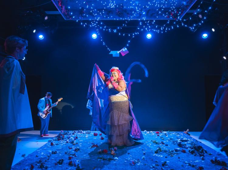 A drag queen singing on stage.
