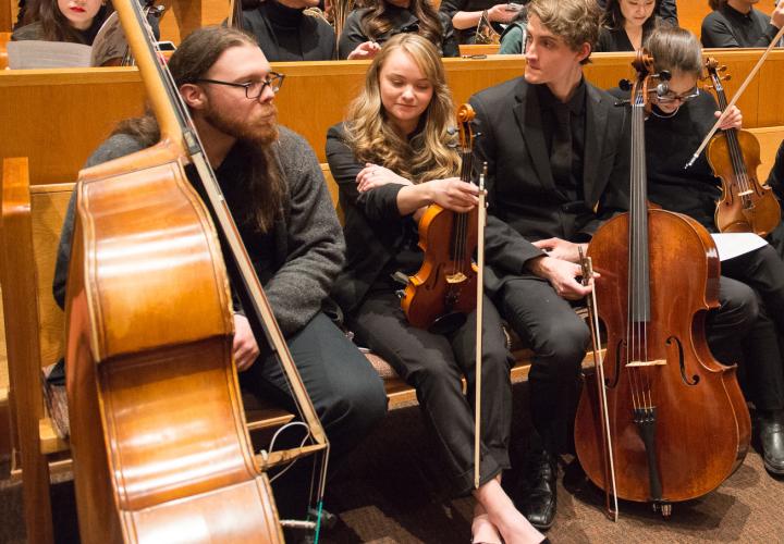 Orchestra students relaxing with their instruments after a performance