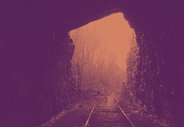 A train track coming out of a tunnel into the light