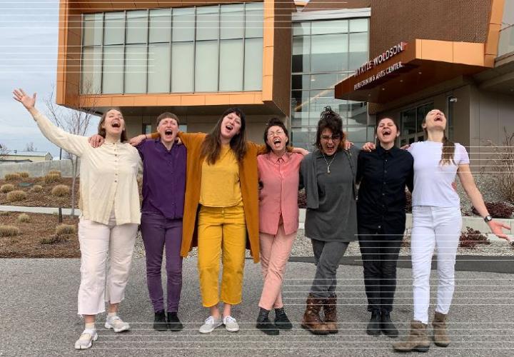 Students yelling or singing in front of a modern architecture buliding.