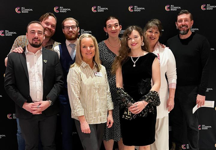 Cast of Puccini operas stand in front of All Classical Radio backdrop
