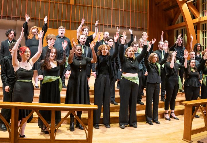 PSU Chamber Choir performing with their arms raised in the air.
