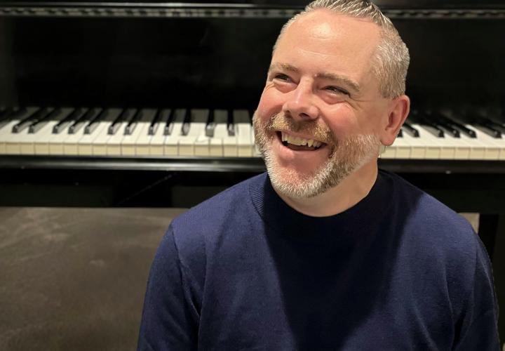 Headshot of PSU Steinway Piano Series guest artist Chad Bowles smiling in front of a piano keyboard.