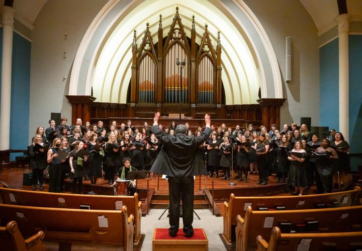 Photo of Dr. Ethan Sperry conducting the PSU Choirs.
