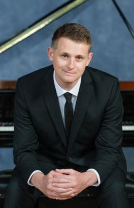 Steinway Piano Series guest artist Tom Hick sitting in front of a piano
