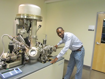Kayode in front of a sputtering chamber