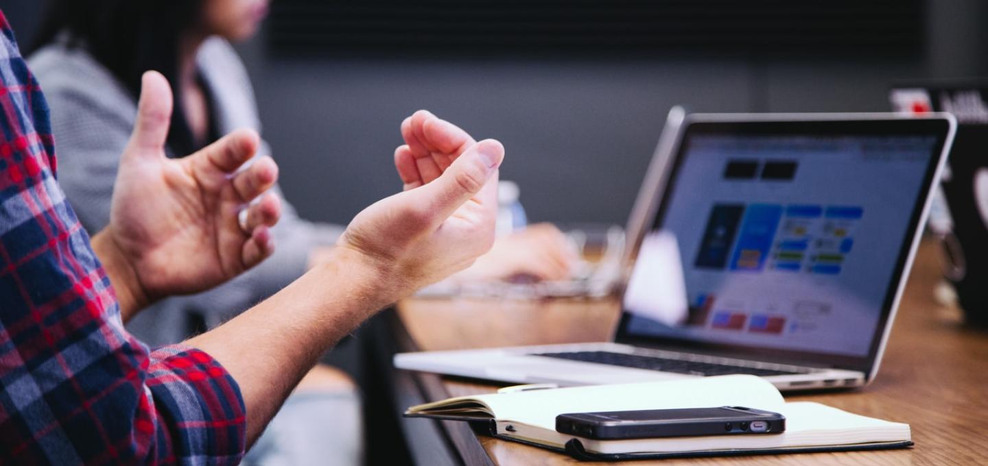 hands making gestures in front of a laptop