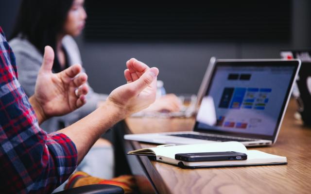 hands making gestures in front of a laptop