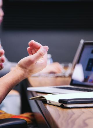 hands making gestures in front of a laptop