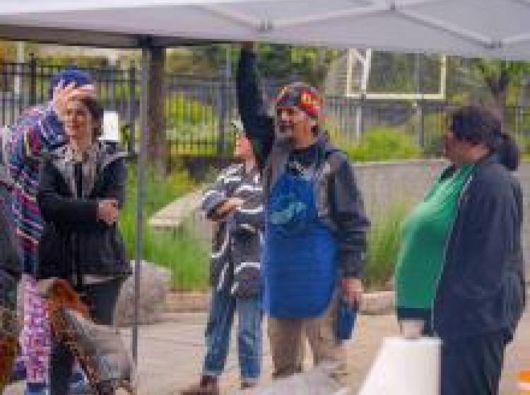 A group of people smoking fish under a canopy