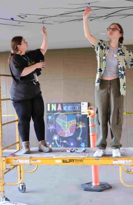 picture of two people painting a mural on a ceiling