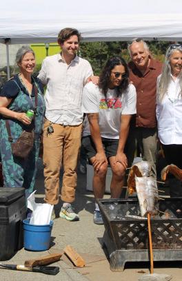 group of people standing in front of baking salmon