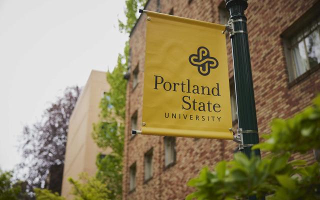picture of a yellow banner sign on a lamp post that reads Portland State university
