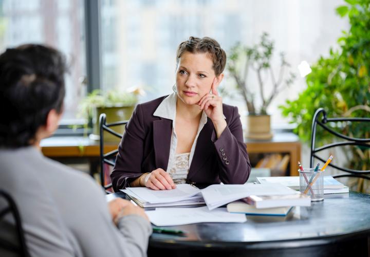 Woman listening to man seated across from her at desk