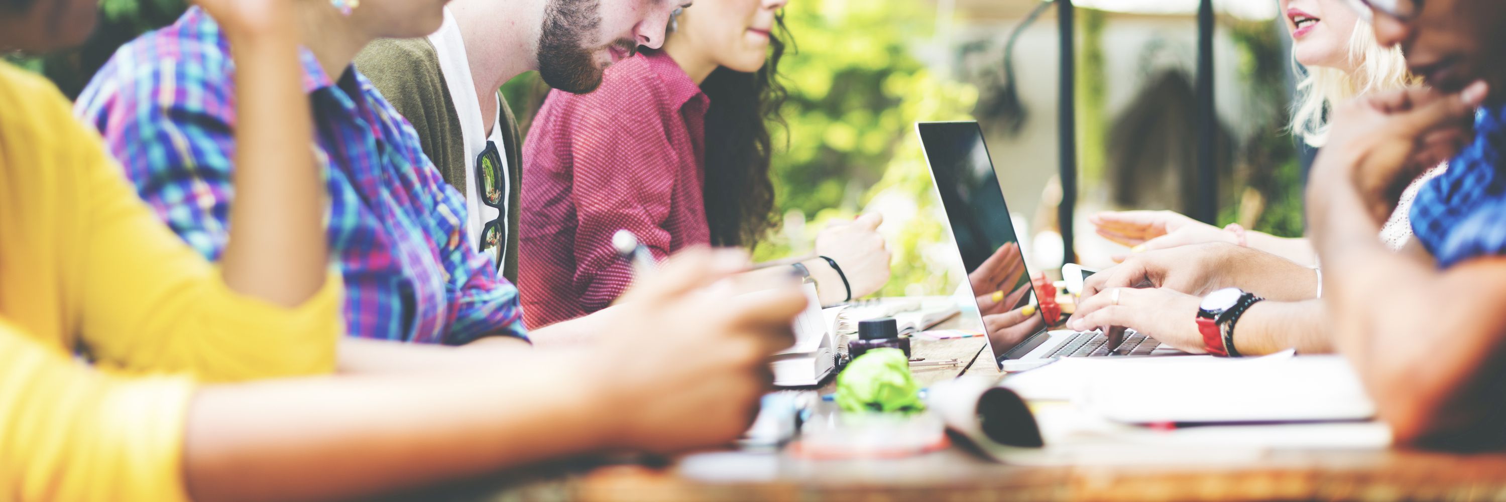 A diverse group of people studying around a table outdoors