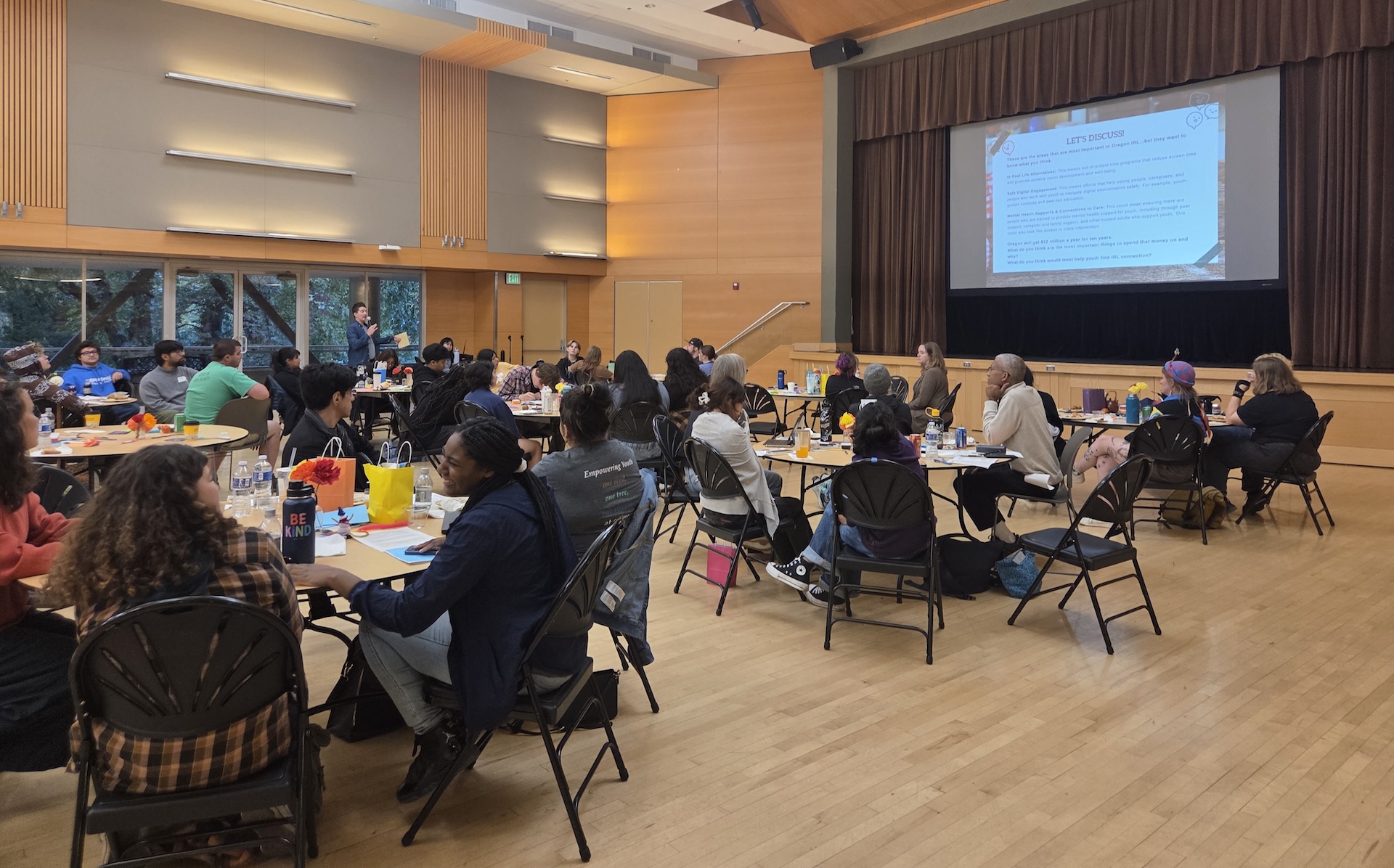 Participants sit around circular tables in several groups to take part in a kitchen table conversation with OKT.