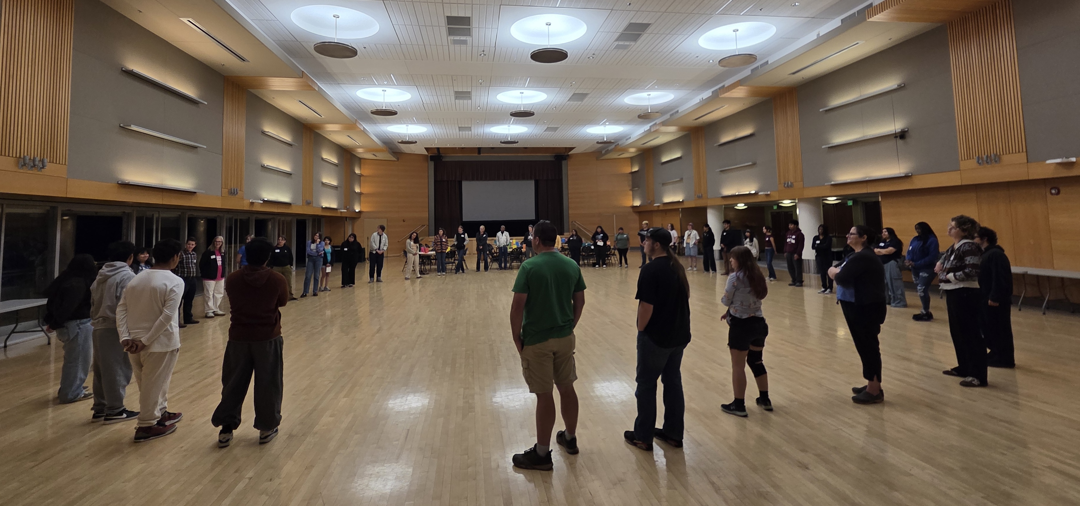 Youth Convening participants stand in a large circle facing inwards.