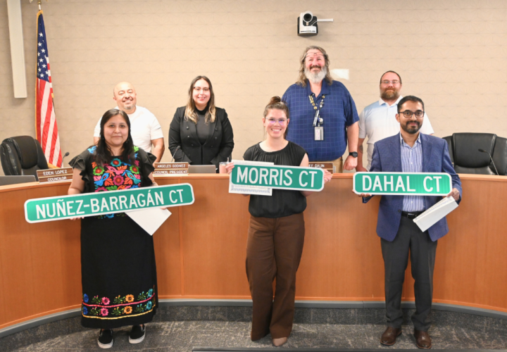 Cornelius Civic Leadership Academy participants stand in front of city council members, holding up street signs with their names on them.