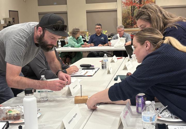 The 2024 Hermiston Civic Leadership Academy participants are working over a table together.