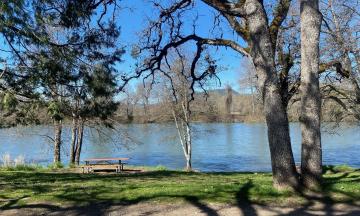 A calm upper Rogue River, with trees and a walking path in the foreground