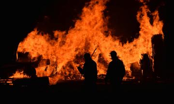 Fire image by ISSY BAILEY via Unsplash: silhouette of two people backlit by tall flames. 