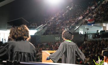 Commencement ceremony at Viking Pavilion, speaker at podium shown from behind. 