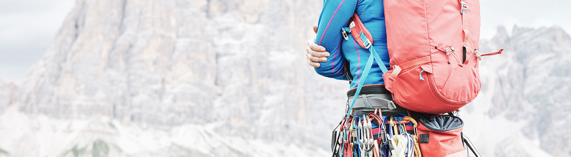 A rock climber in professional gear looking at a mountain