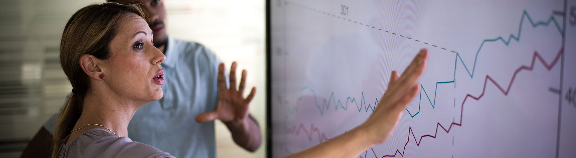 Woman presenting at large touch screen with charts