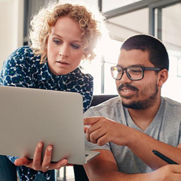 Two people working together looking at a laptop 