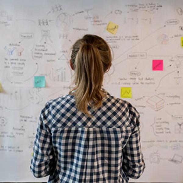 Woman in front of whiteboard covered with notes
