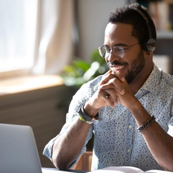 Man with headphones smiling at computre screen.