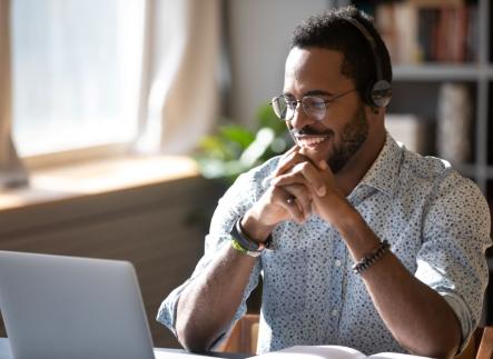 Man with headphones smiling at computre screen.