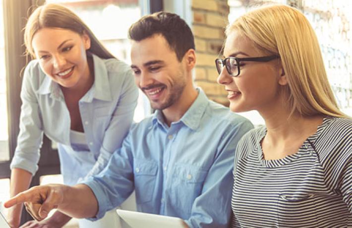 Group of 3 people smiling at their computers while working