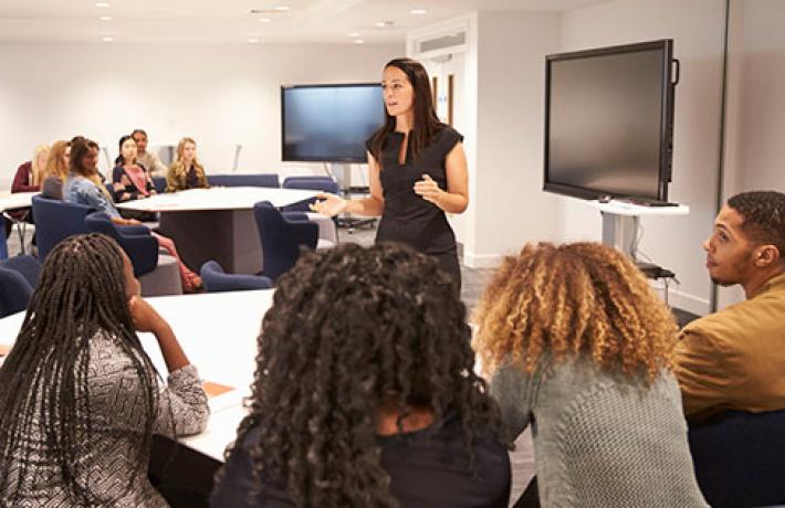 Female teacher addressing university students in a classroom