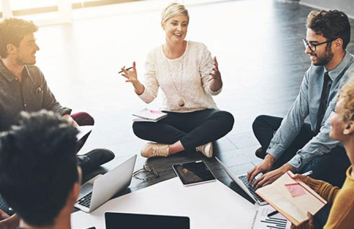 Woman leading a meeting sitting on the floor in a circle