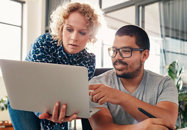 Two people working together looking at a laptop