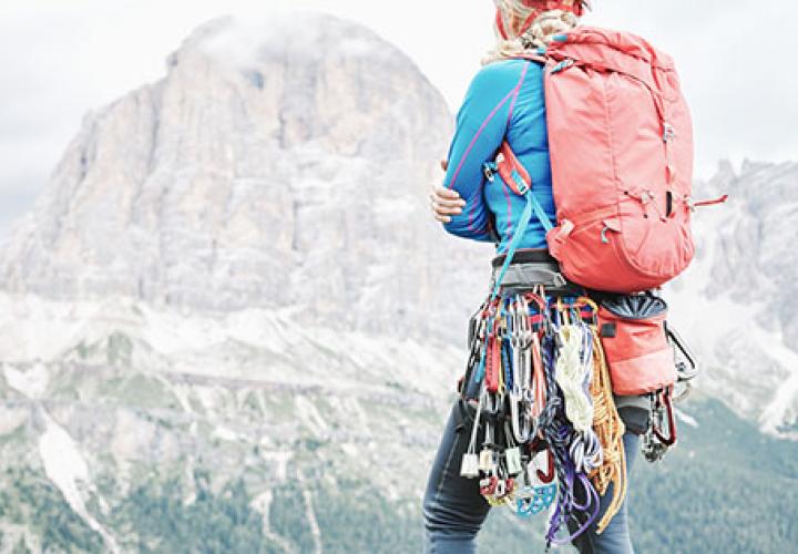 Climber with gear and pack looking at mountain in the distance