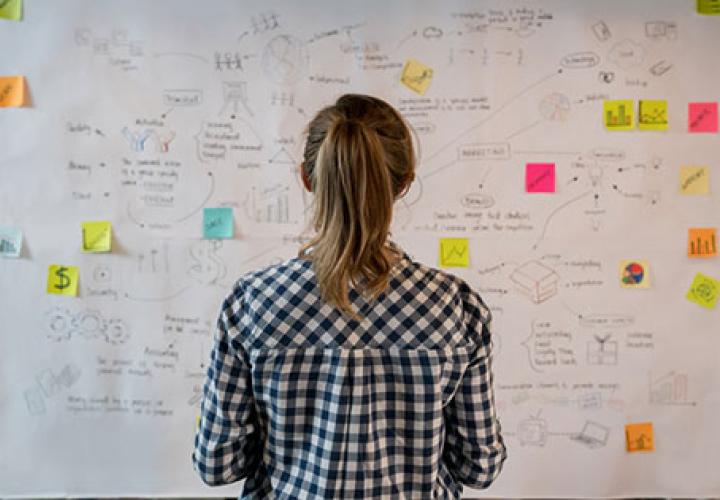 Woman in front of whiteboard covered with notes